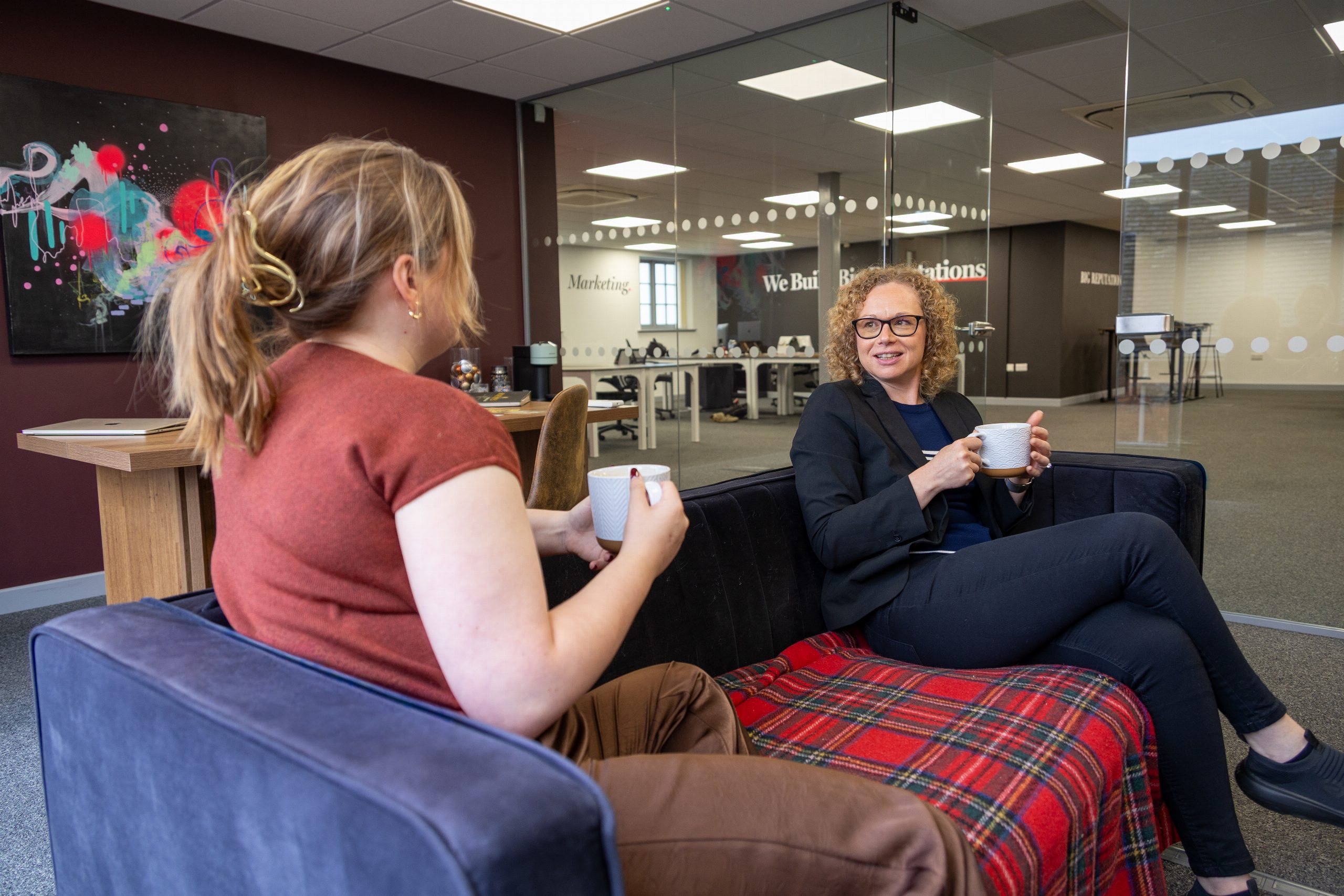 Joanne Tryner and a Big Reputation team member talking on a sofa