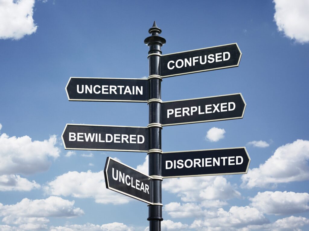 Signpost against a blue sky with arrows reading confused, uncertain, perplexed, bewildered, disoriented and unclear